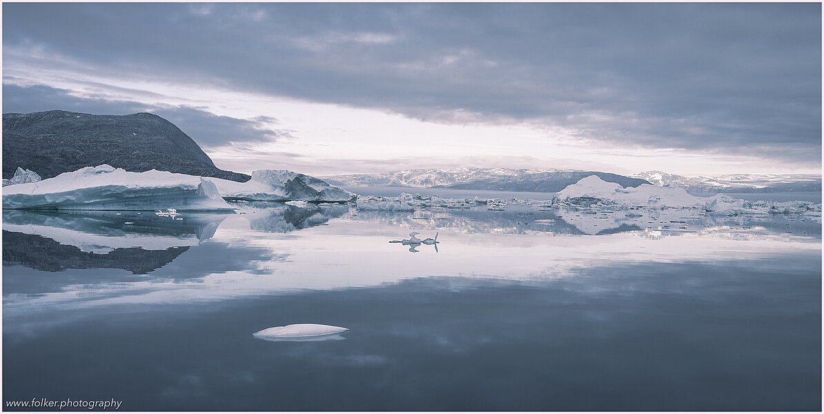 This fine-art photograph provides a beautiful view on icebergs at the Sermilik fjord in East-Greenland.