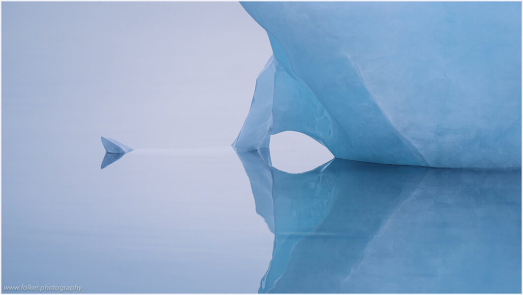 This fine-art photograph shows a minimalistic detail of an iceberg with refection in the water. Picture was taken at the Sermilik fjord in East-Greenland. 