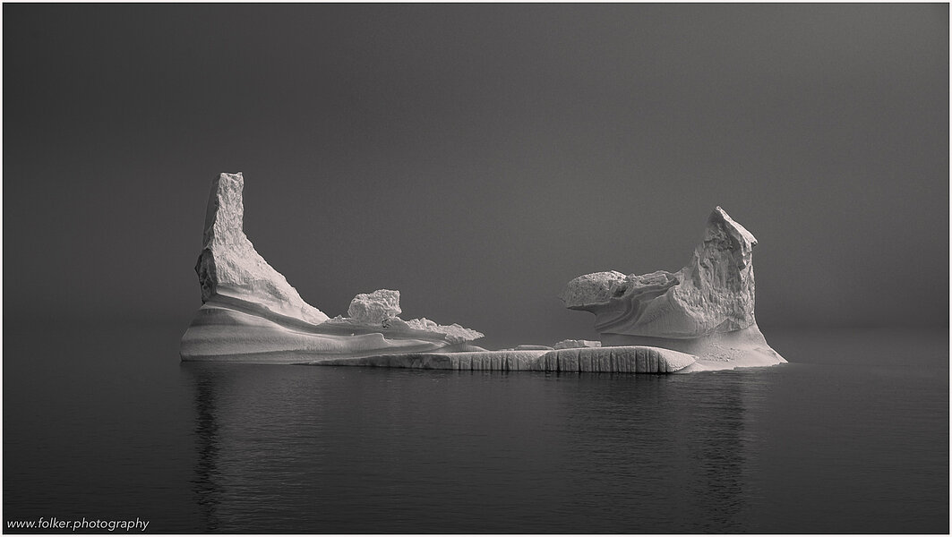 This fine-art photograph showing a well-shaped iceberg in misty conditions in black and white.  Picture was taken near Tassilaq in East-Greenland.