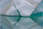 This fine-art photograph shows a minimalistic detail of an iceberg with reflection in the water. Nature created a beautiful abstract with cracks and layer of ice colors. Picture was taken at the Sermilik fjord in East-Greenland.