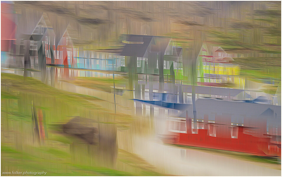 This fine-art photograph shows an abstract, painterly street scene in Tassilaq in East-Greenland. In a style of a painting from early 20th century, you can imagine colorful houses and a pathway 